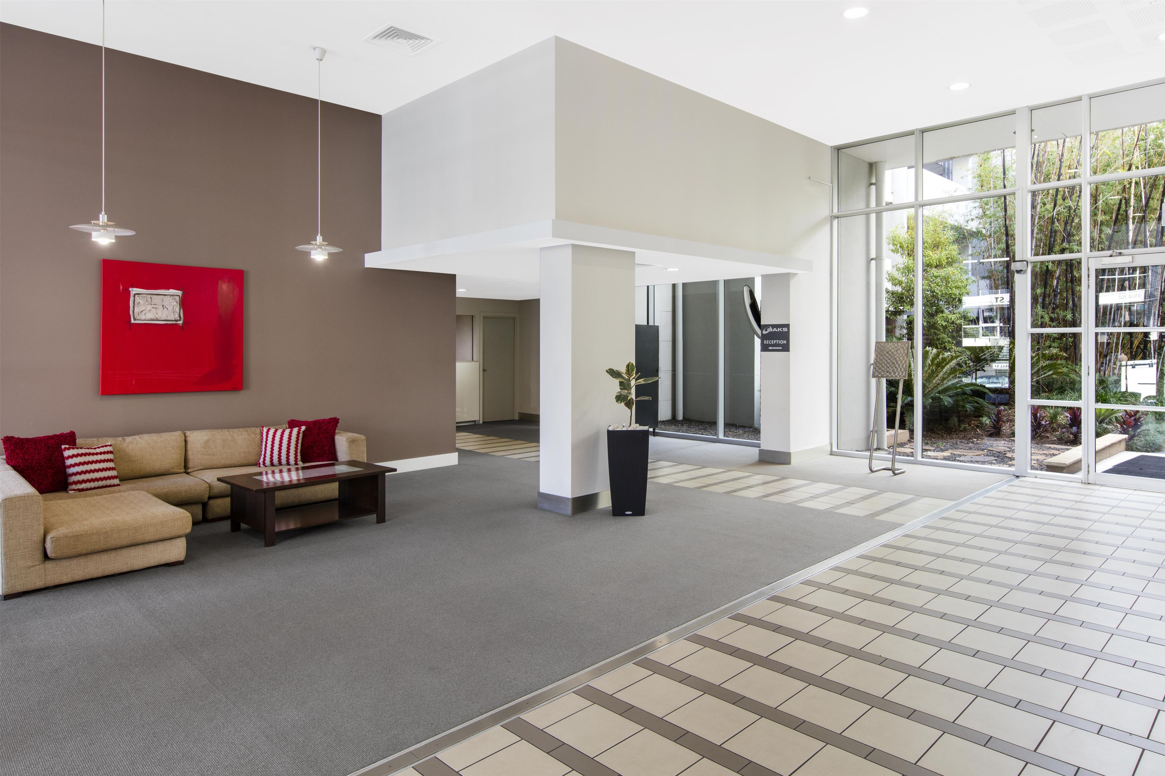 A modern lobby with a sofa, a red artwork, and a reception desk.