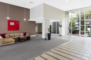 A modern lobby with a sofa, a red artwork, and a reception desk.