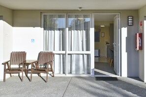 A building entrance with a sliding glass door, a fire extinguisher, and a wheelchair accessibility sign. - The Riverstone (Rangiora)