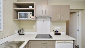 A compact kitchen with a microwave, kettle, and a dishwasher. - The Riverstone (Rangiora)