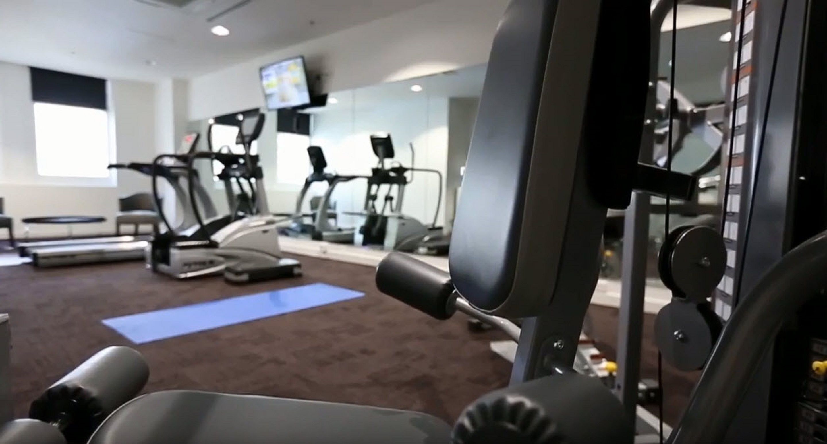 A gym with exercise equipment, a treadmill, and a blue mat.