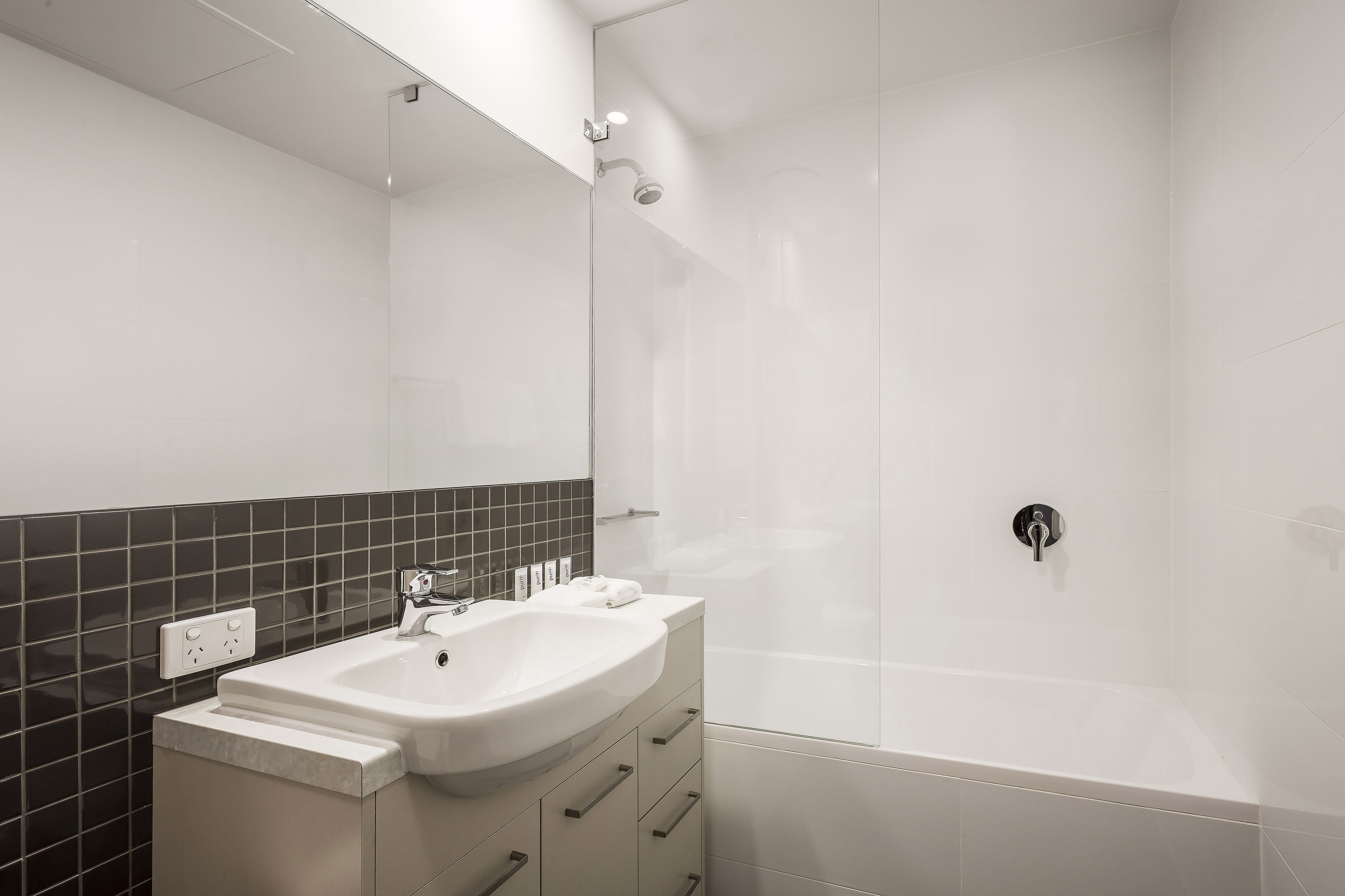 A modern bathroom with a white sink, mirror, and shower.