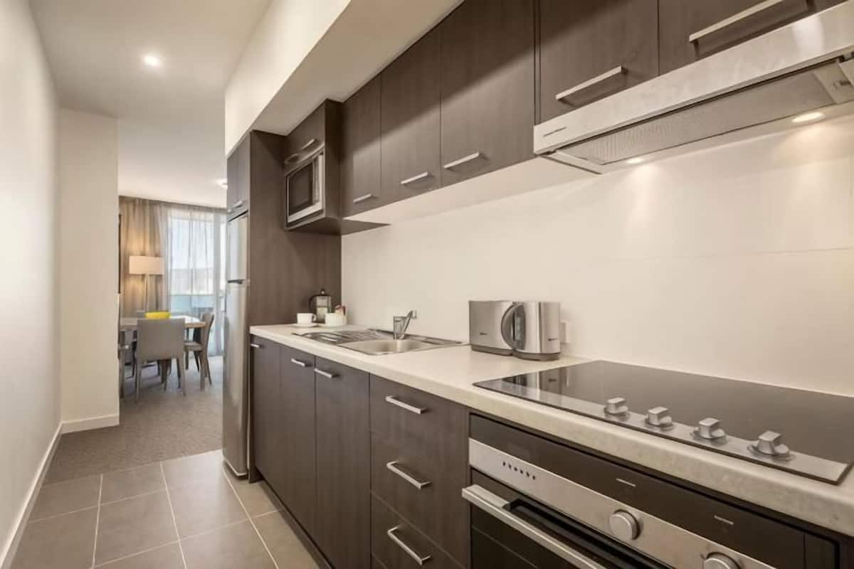 Uma cozinha moderna com armários escuros, eletrodomésticos de aço inoxidável e uma bancada ampla.