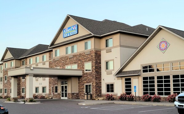 A multi-story hotel with a stone facade, a prominent AmeriVul Inn & Suites sign, and a parking lot.