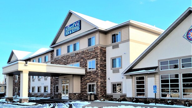 Un hotel de varios pisos con fachada de piedra, entrada cubierta y un cartel que dice AmeriVu Inn & Suites.