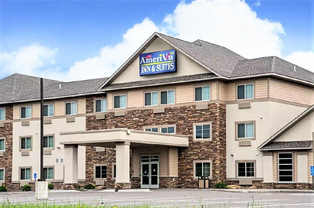 Een meerhoog hotel met een gevel van natuursteen en een bord met AmeriVu Inn & Suites.