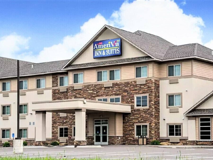 Een meerhoog hotel met een gevel van natuursteen en een bord met AmeriVu Inn & Suites.