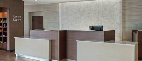 A reception desk with a digital screen, a corner market sign, and a patterned wall.