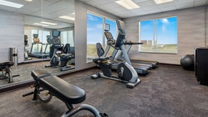 A gym with exercise equipment, a bench, a mirrored wall, and large windows. - Fairfield Inn & Suites Alamosa (Alamosa)