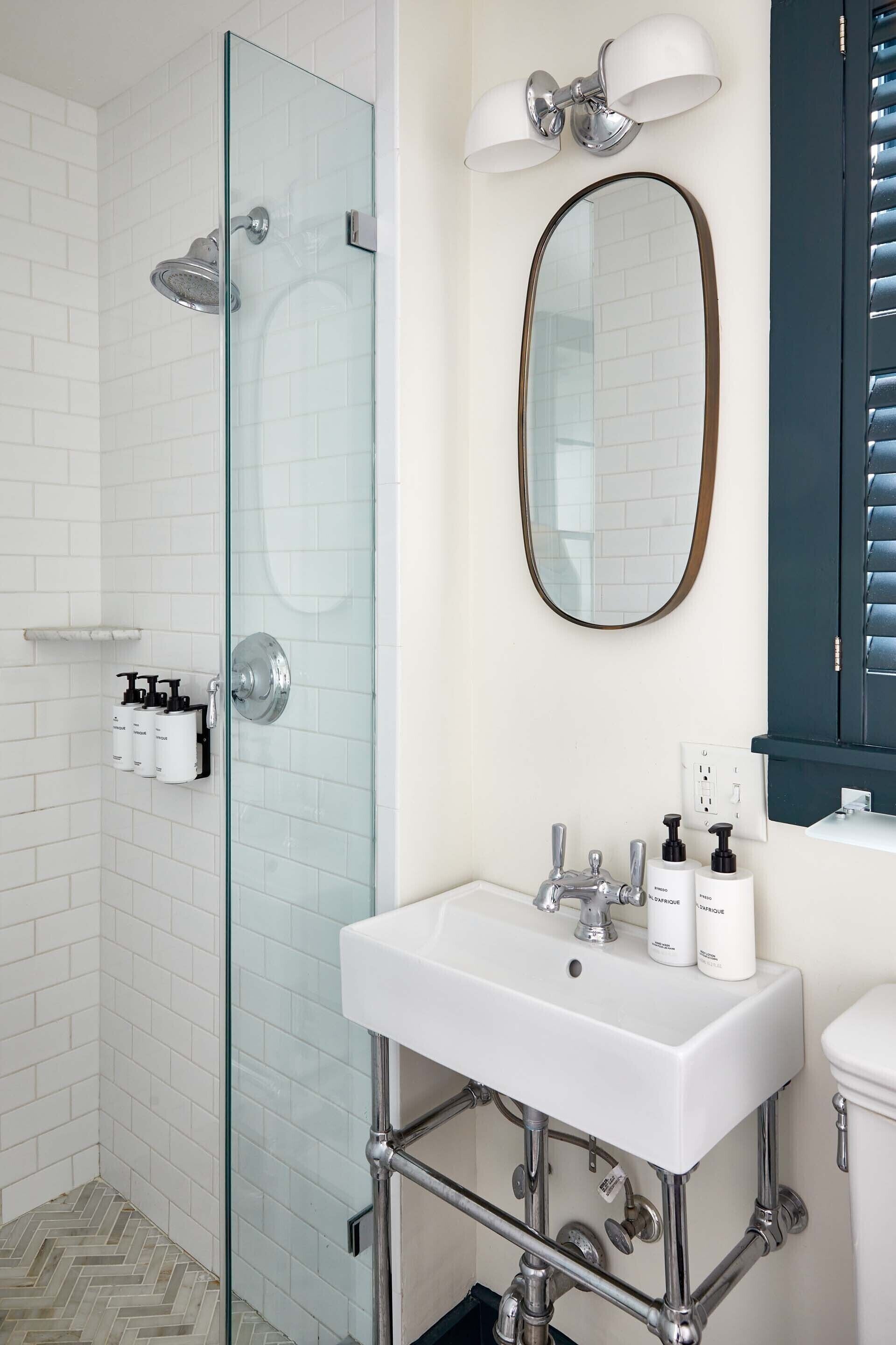 A modern bathroom with a glass shower enclosure, a white sink with chrome fixtures, and a mirror above the sink.