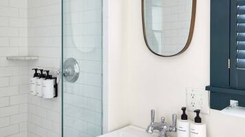 A modern bathroom with a glass shower enclosure, a white sink with chrome fixtures, and a mirror above the sink.