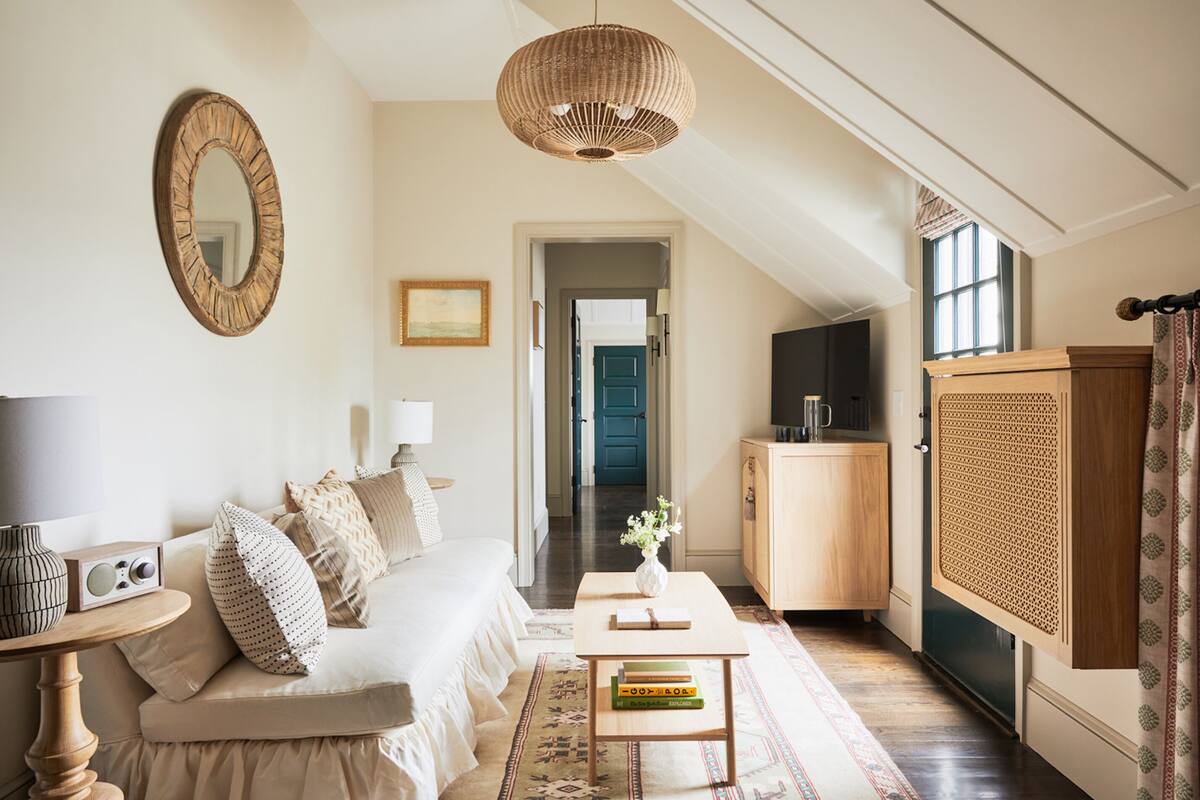 A cozy living room with a sofa, a coffee table, a bookshelf, a mirror, and a television.