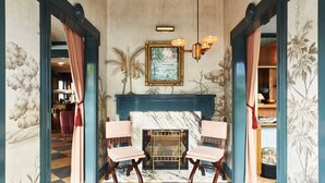 A room with a checkered floor, a fireplace, two striped chairs, and a framed painting above the fireplace. - Faraway Nantucket (Nantucket)