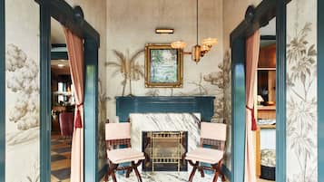 Cozy retreat with a fireplace, comfortable chairs, and elegant chandelier.