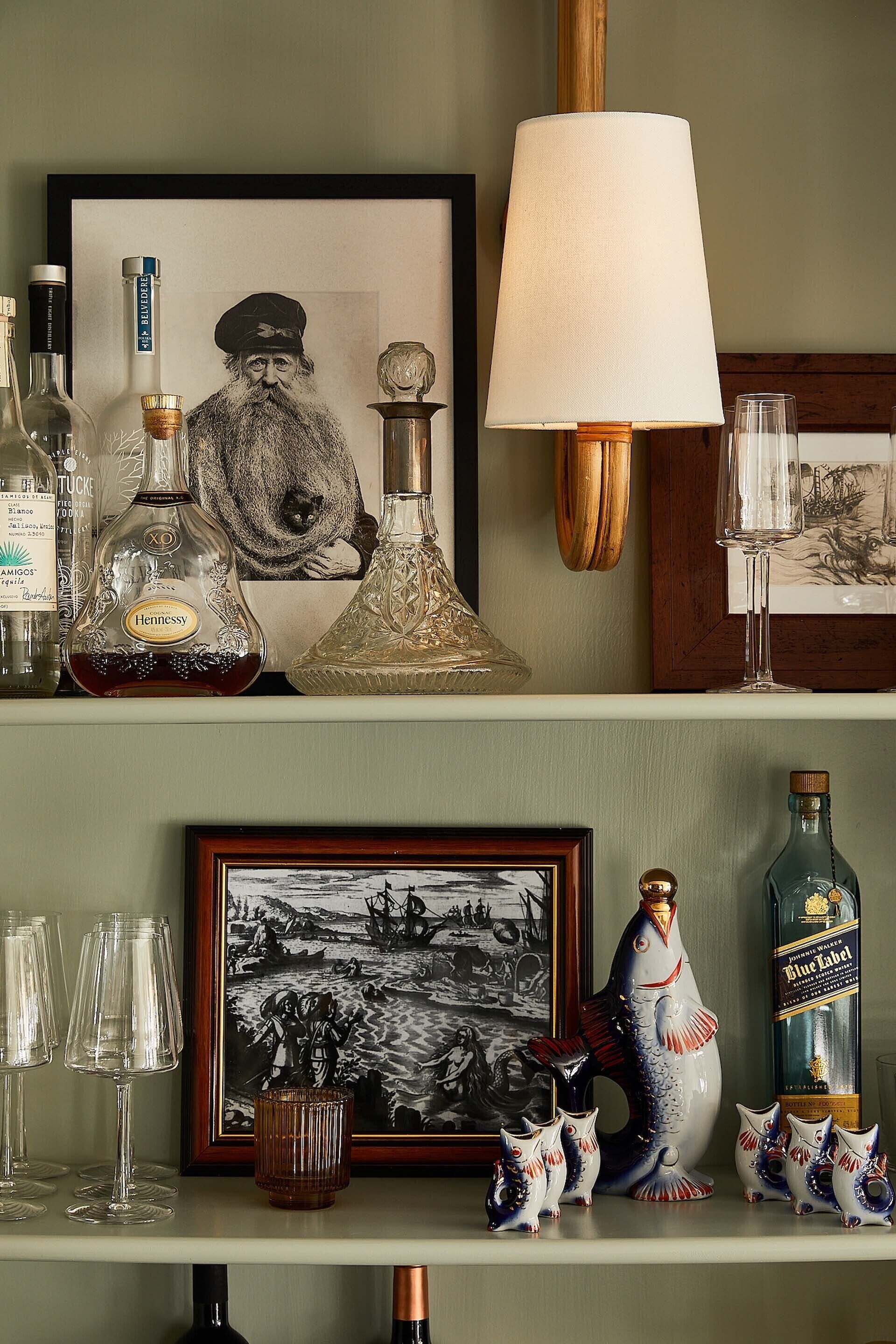 Una estantería con varias botellas, un cuadro enmarco y objetos decorativos.