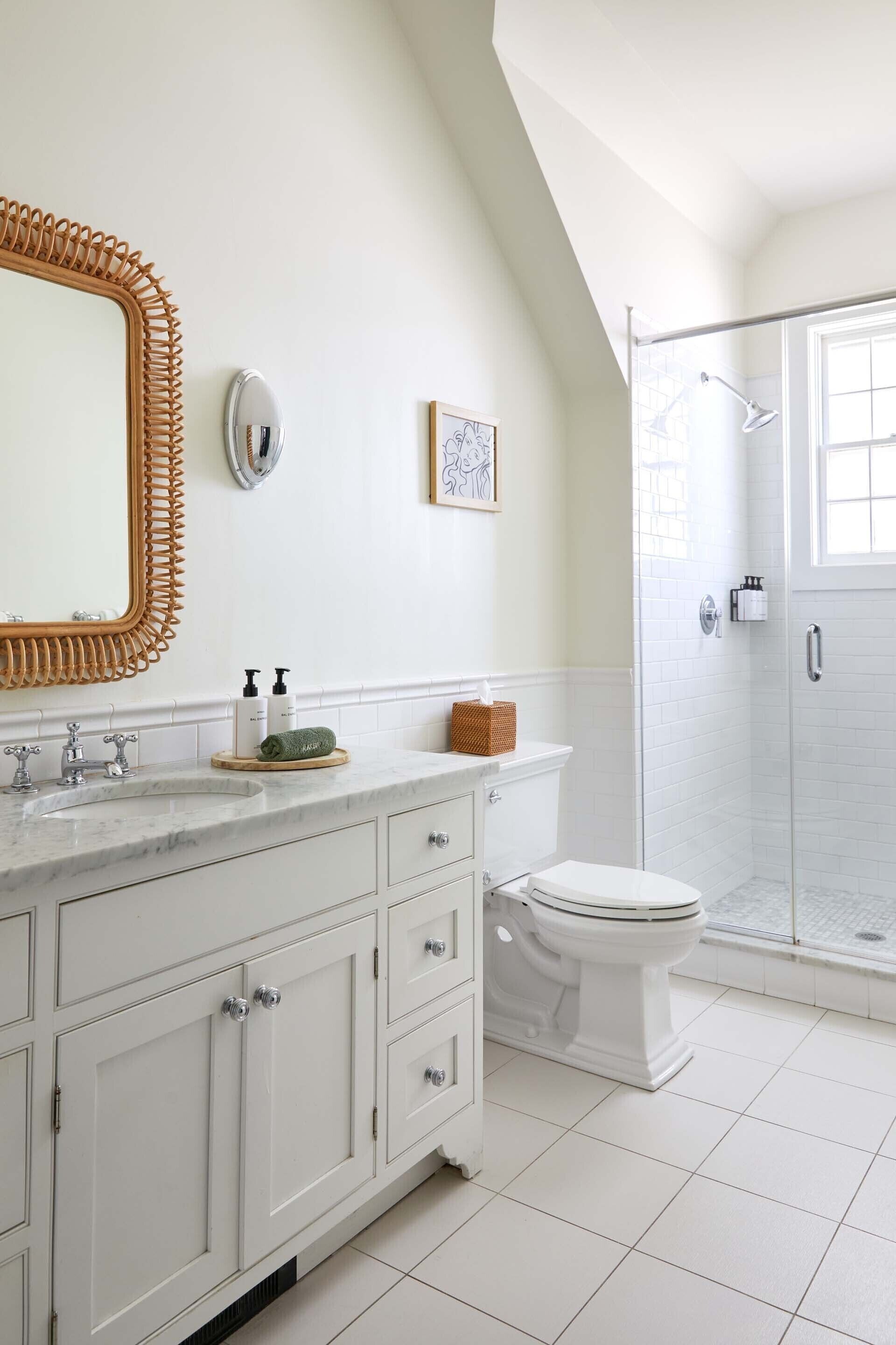 A bathroom with a white vanity, a large mirror, a toilet, and a walk-in shower.