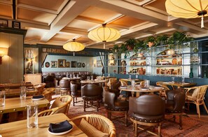 A restaurant interior with wooden tables, wicker chairs, and hanging lanterns.