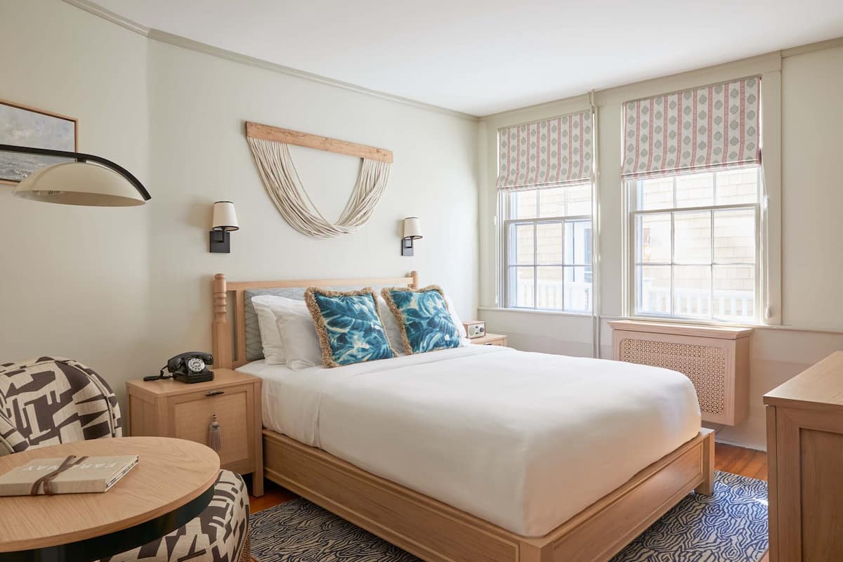 A neatly arranged bedroom with a bed, bedside tables, a lamp, and a chair.