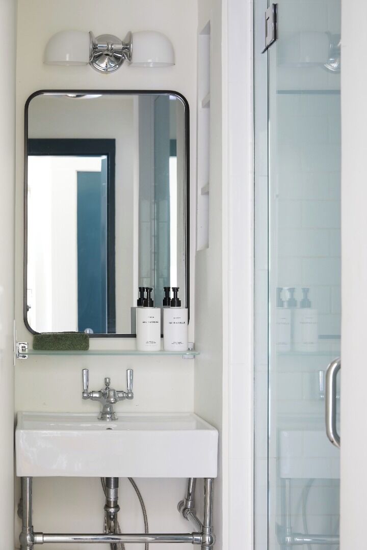 A bathroom with a mirror, a sink, and a glass shower enclosure.