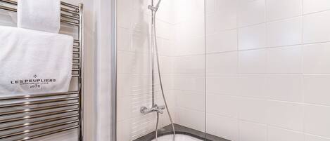 Un baño moderno con ducha envuelta en cristal, toallero con toallas blancas y bañera con encimera de granito.