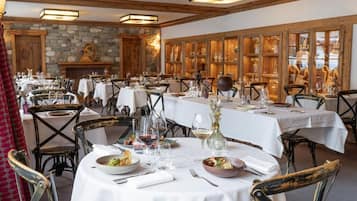 Un restaurante con mesas redondas dispuestas para comer, con manteles blancos y sillas de madera.
