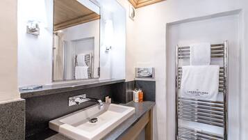 Un baño moderno con un espejo grande, un lavamanos, un perchero para toallas y una zona de ducha.