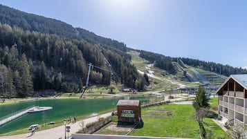 A lakeside hotel with a view of a mountain, a ski lift, and a small dock.