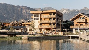 Een meerhoog hotel met balkons, een bord en uitzicht op bergen op de achtergrond.
