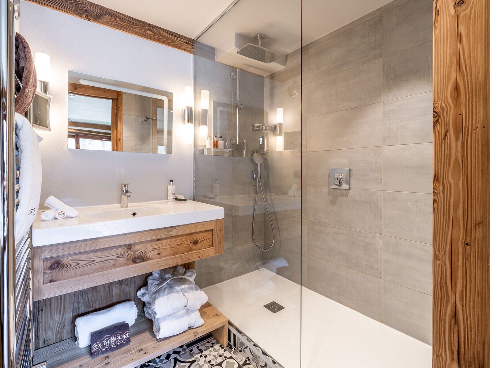 A modern bathroom with a wooden vanity, a glass shower enclosure, and a large mirror.