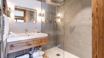 Une salle de bain moderne avec un meuble-lavabo en bois, une cabine de douche en verre et un grand miroir.