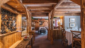 A rustic wooden interior with a central dining area, wooden shelves with wine bottles, and a cozy atmosphere. - Hôtel Les Peupliers (Courchevel)