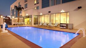 A swimming pool with lounge chairs and a palm tree, adjacent to a building with a sign that reads "Hotel". - Springhill Suites Houston I-45 North (Houston)