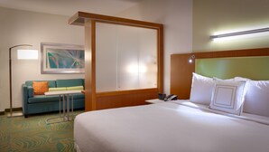 A hotel room with a bed, a sofa, a desk, a phone, and a painting on the wall. - Springhill Suites Houston I-45 North (Houston)