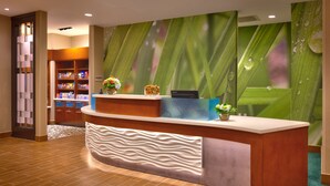A reception desk with a modern design, a water feature, and a backdrop of green leaves. - Springhill Suites Houston I-45 North (Houston)