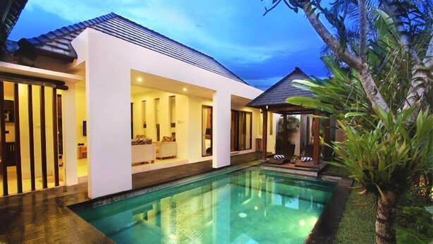 Una casa moderna con piscina, un espacio exterior cubierto y un jardín cuidado.