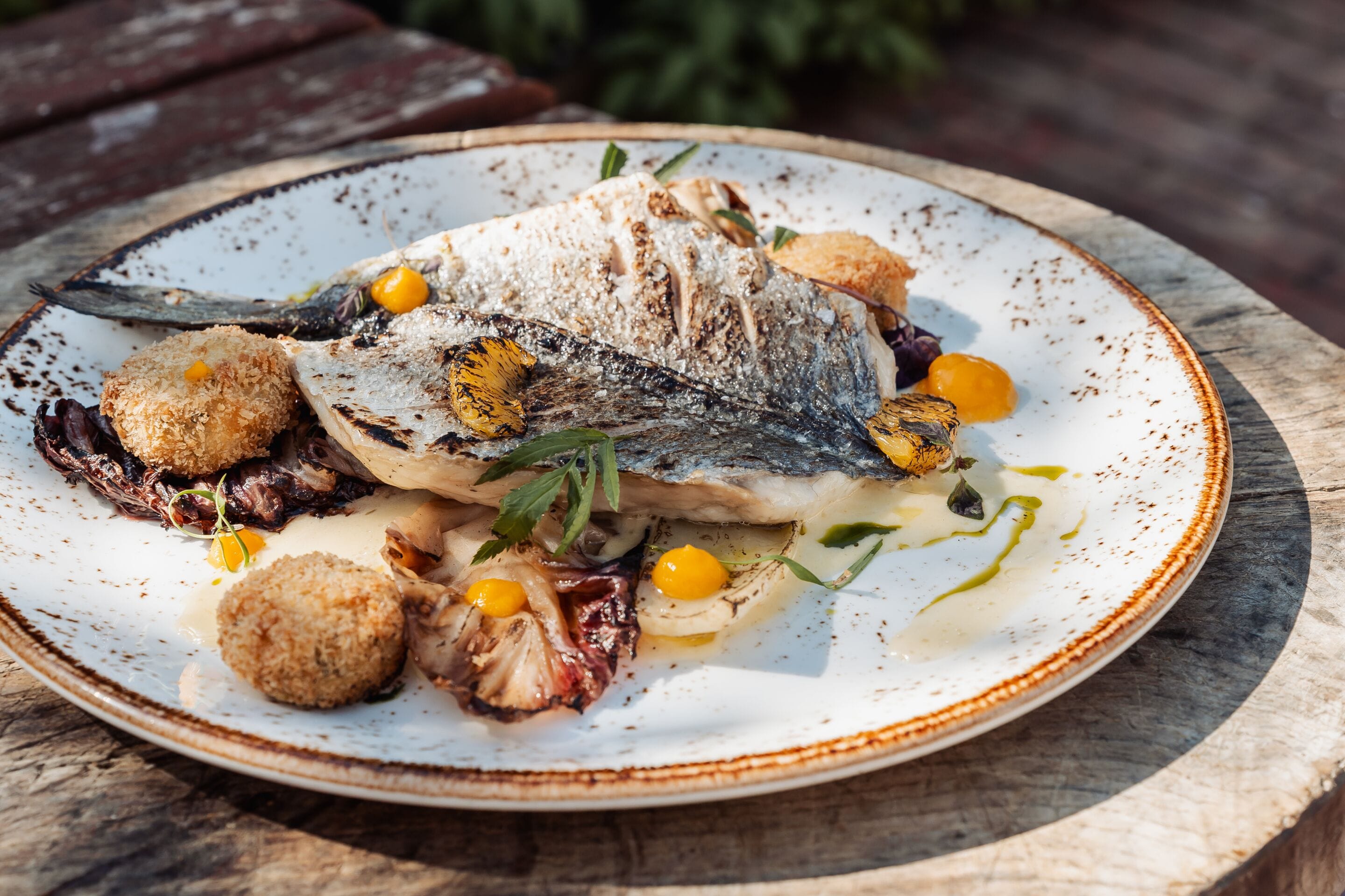 Un plato de comida con pescado, verduras asadas y guarniciones.