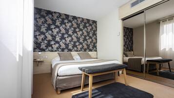 A modern bedroom with a bed, bench, and a large mirror.