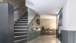 Un intérieur moderne agrémenté d’un escalier, d’une console en verre et d’un mur décoratif.