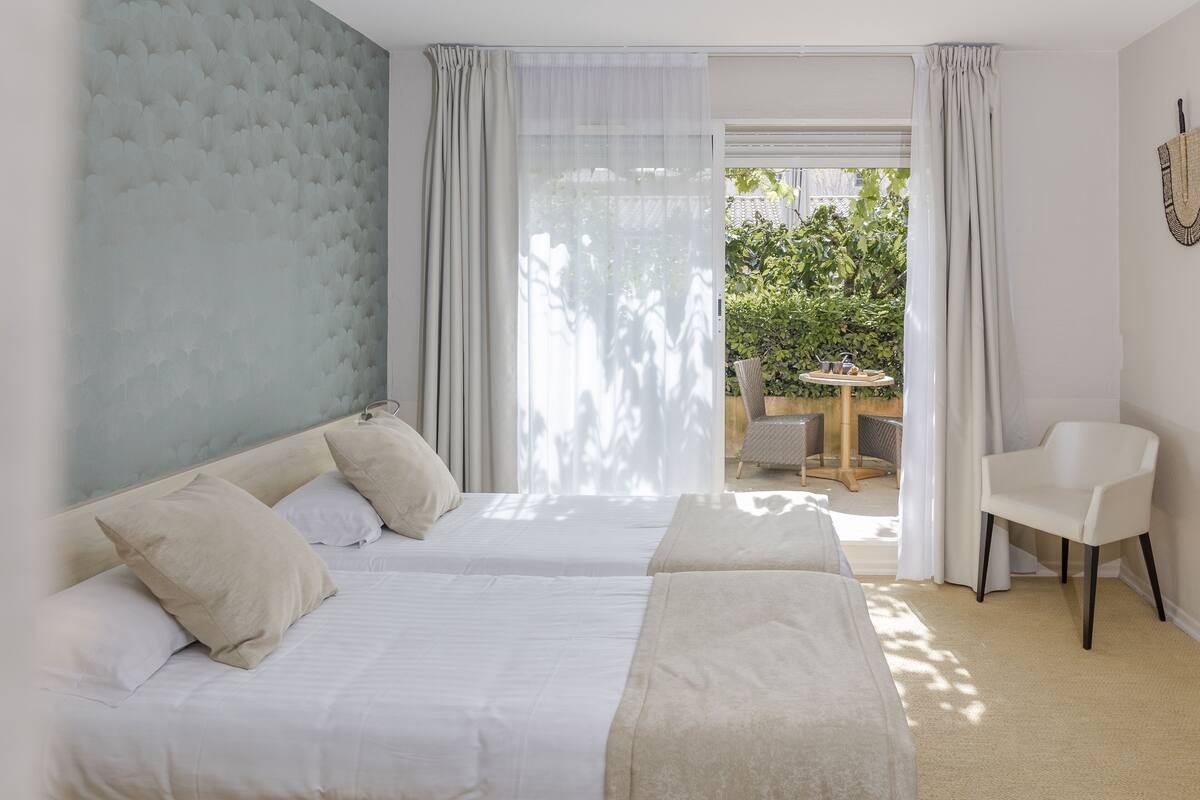 A hotel room with two beds, a small table, and a chair.