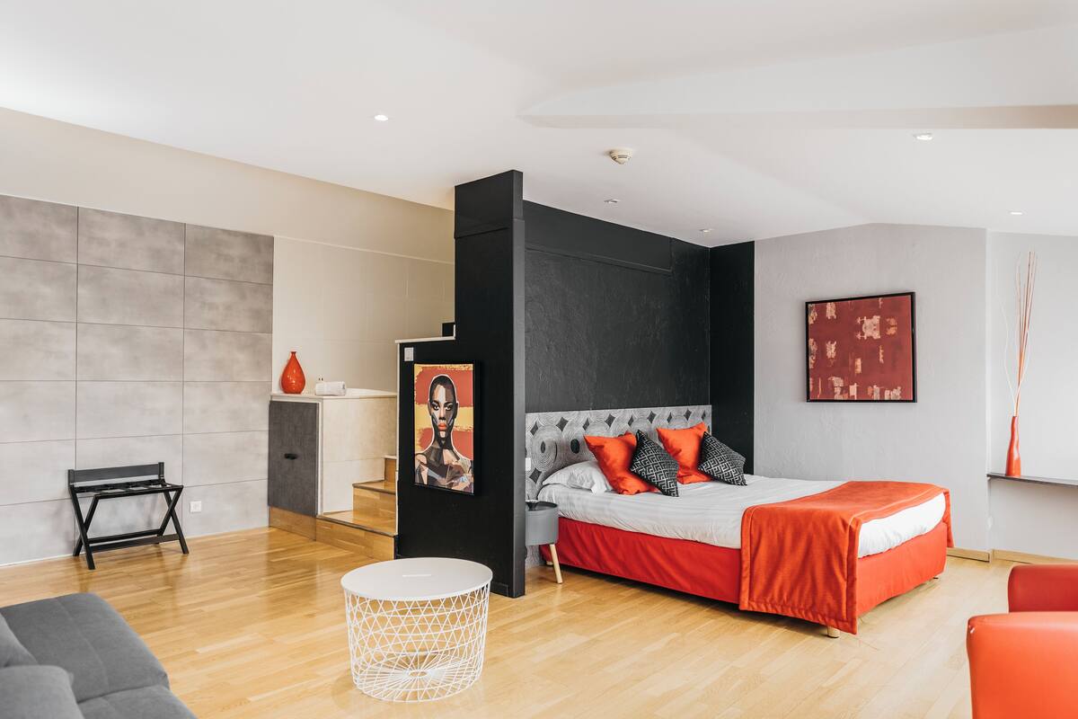 A modern bedroom with a bed, a desk, a chair, and a round white table.