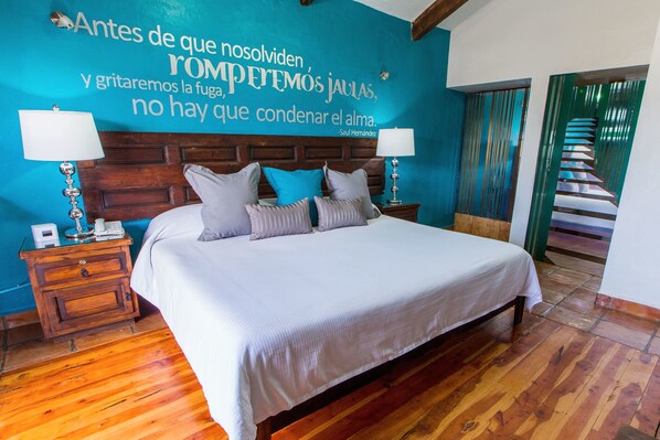 Cozy retreat with a large bed, two nightstands, and a spiral staircase leading to an upper level.