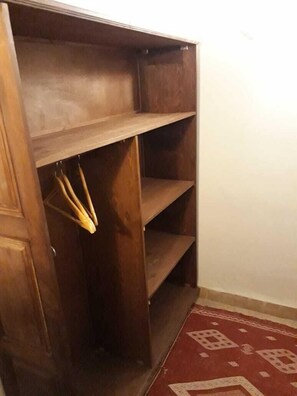 A wooden wardrobe with multiple shelves and hanging space. - Riad Le Sucrier De Fès (Fes)