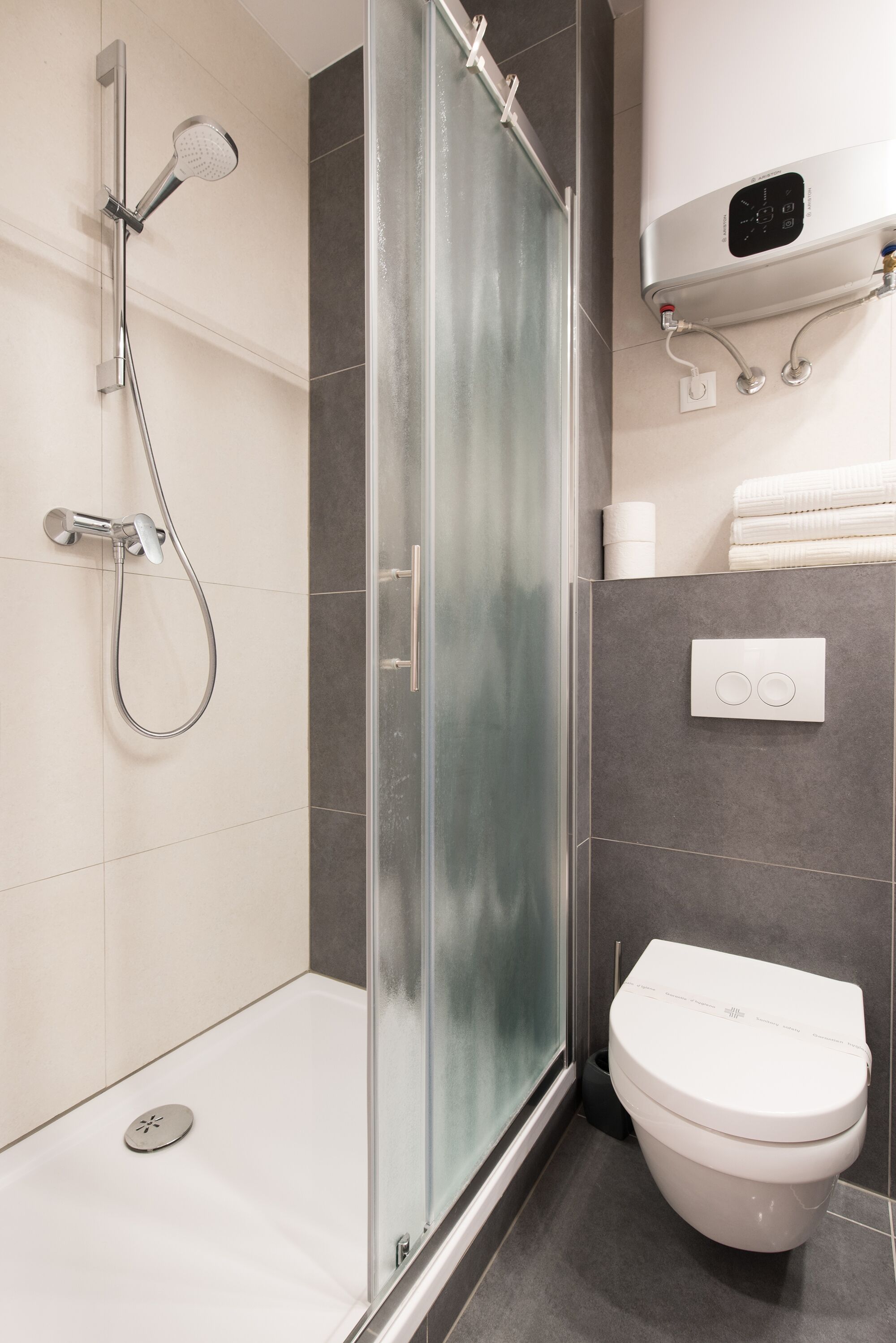 Un baño moderno con cabina de ducha de vidrio, inodoro blanco y un perchero para toallas.
