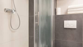 Un baño moderno con cabina de ducha de vidrio, inodoro blanco y un perchero para toallas.
