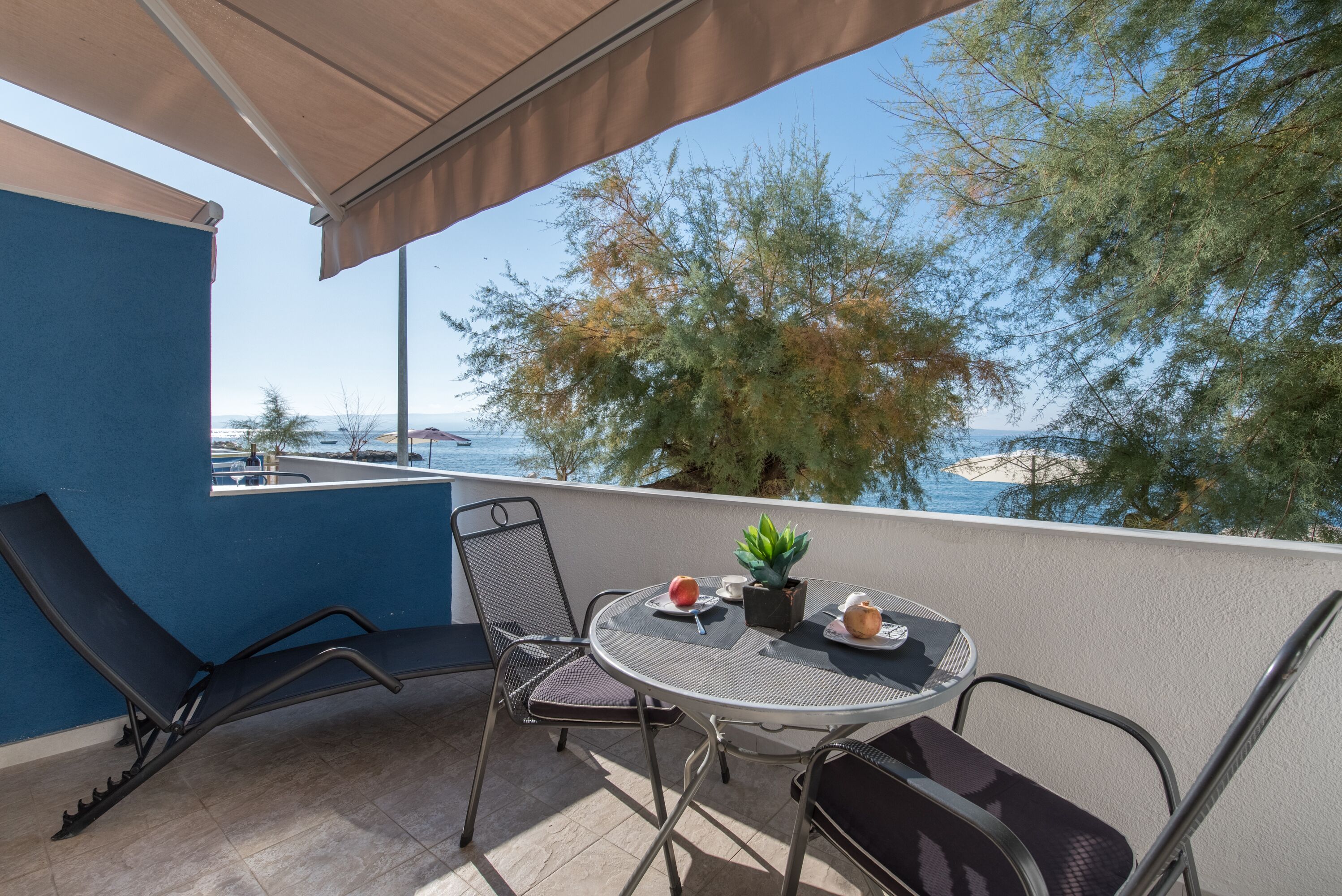 A balcony with a table, chairs, and a potted plant.