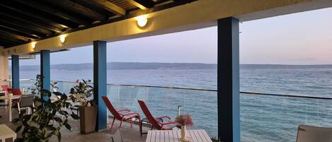 An outdoor seating area with tables and chairs, overlooking a body of water.