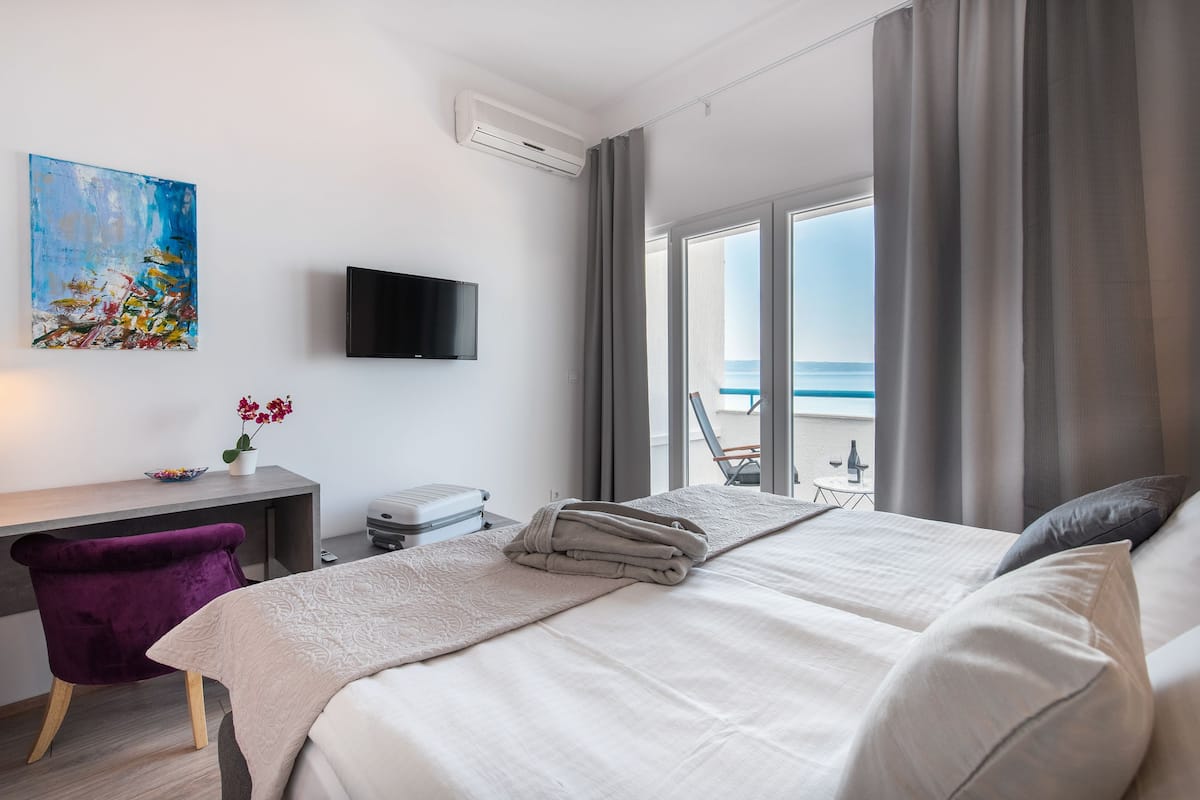 A hotel room with a bed, a desk, a chair, a TV, and a painting.
