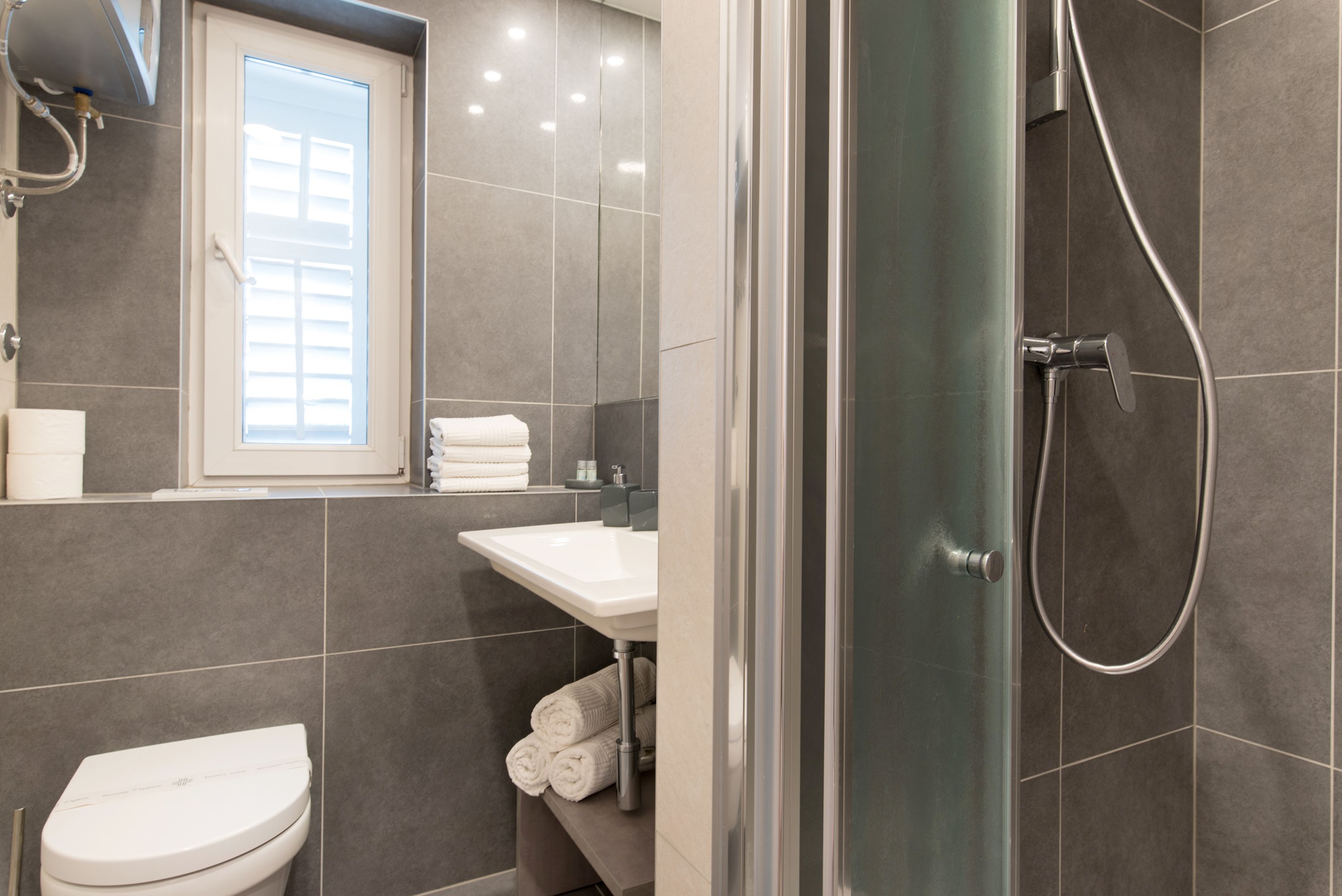 Un baño moderno con inodoro, lavamanos y ducha.