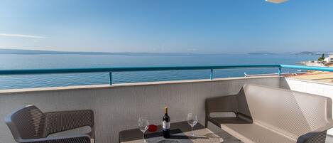 A balcony with a table, two chairs, a bottle of wine, and two glasses.