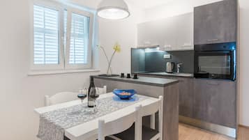 A modern kitchen with a dining area, featuring a white table, chairs, and a blue bowl.